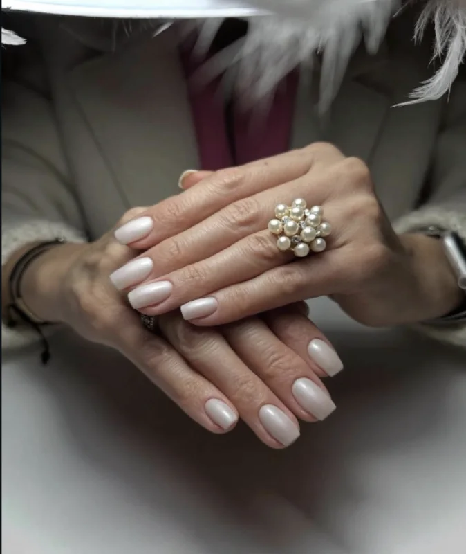 Pose blanche nacrée sur ongles courts, portée avec une bague à perles