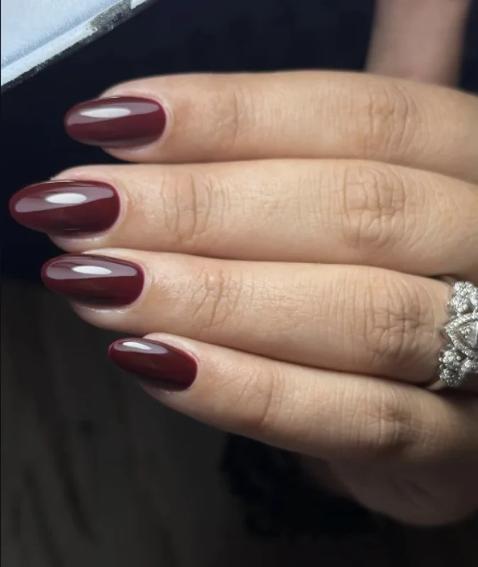 Pose permanente bordeaux brillante sur ongles en amande