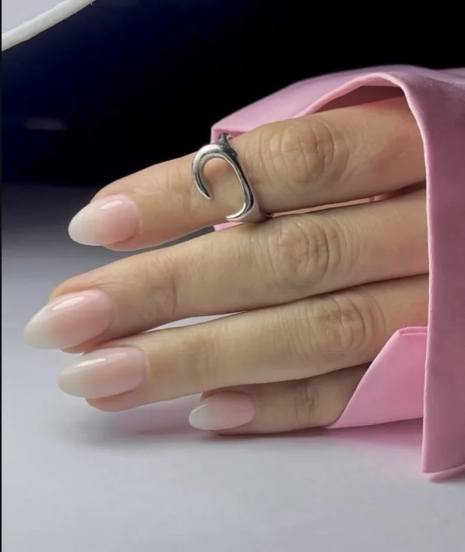 Ongles en amande, dégradé nude, main posée sur un sac rose