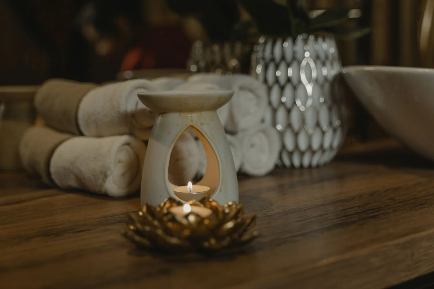 Serviettes roulées et brûle-parfum doré, dans une ambiance chaude et calme