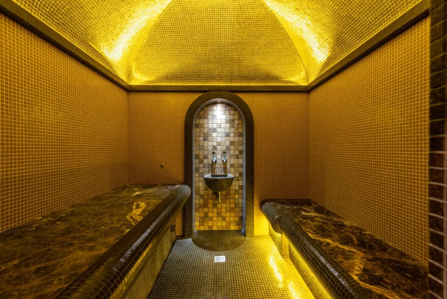 Salle de hammam en mosaïque, éclairée d'une lumière dorée