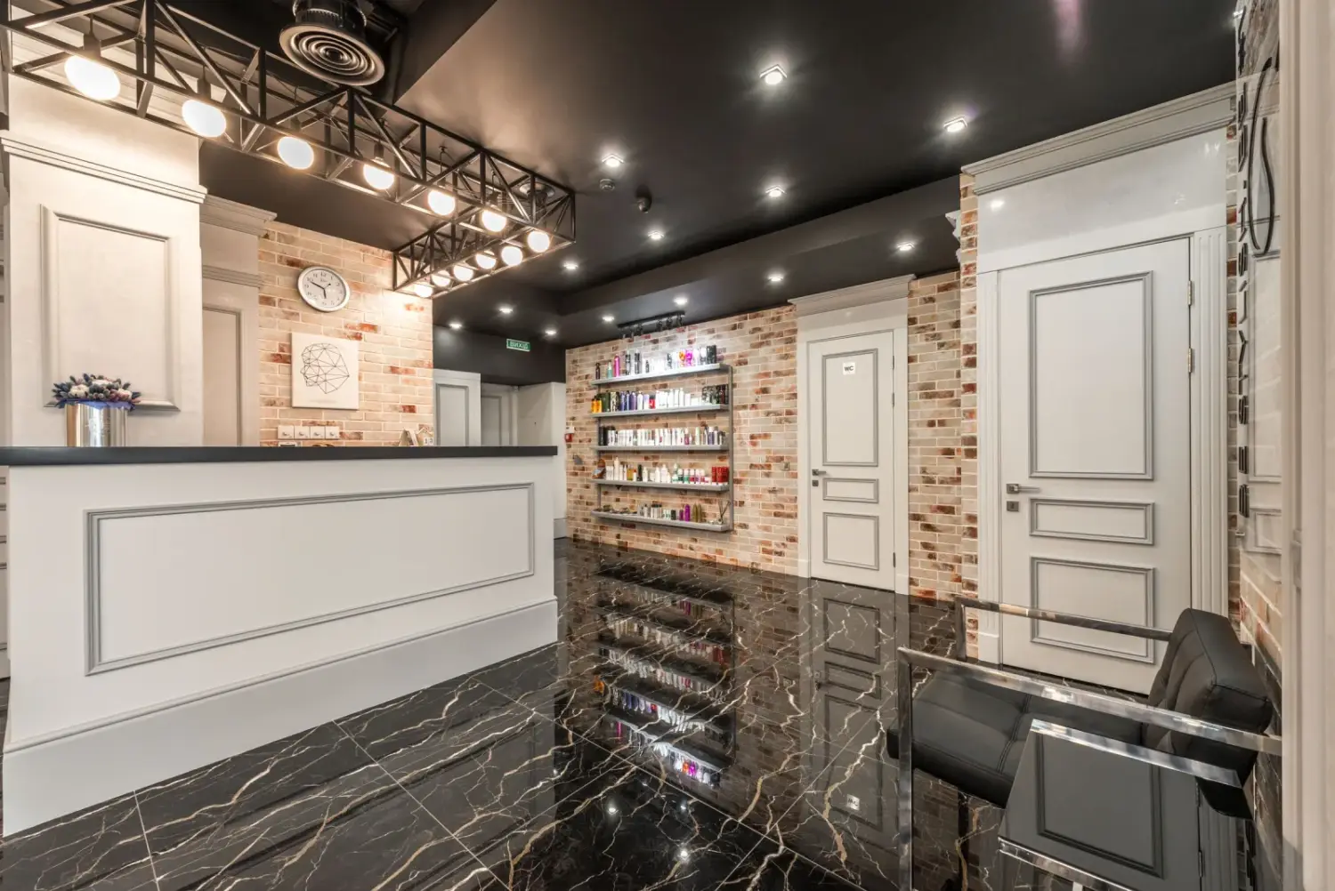Intérieur de salon de beauté au sol de marbre sombre, éclairé de suspensions
