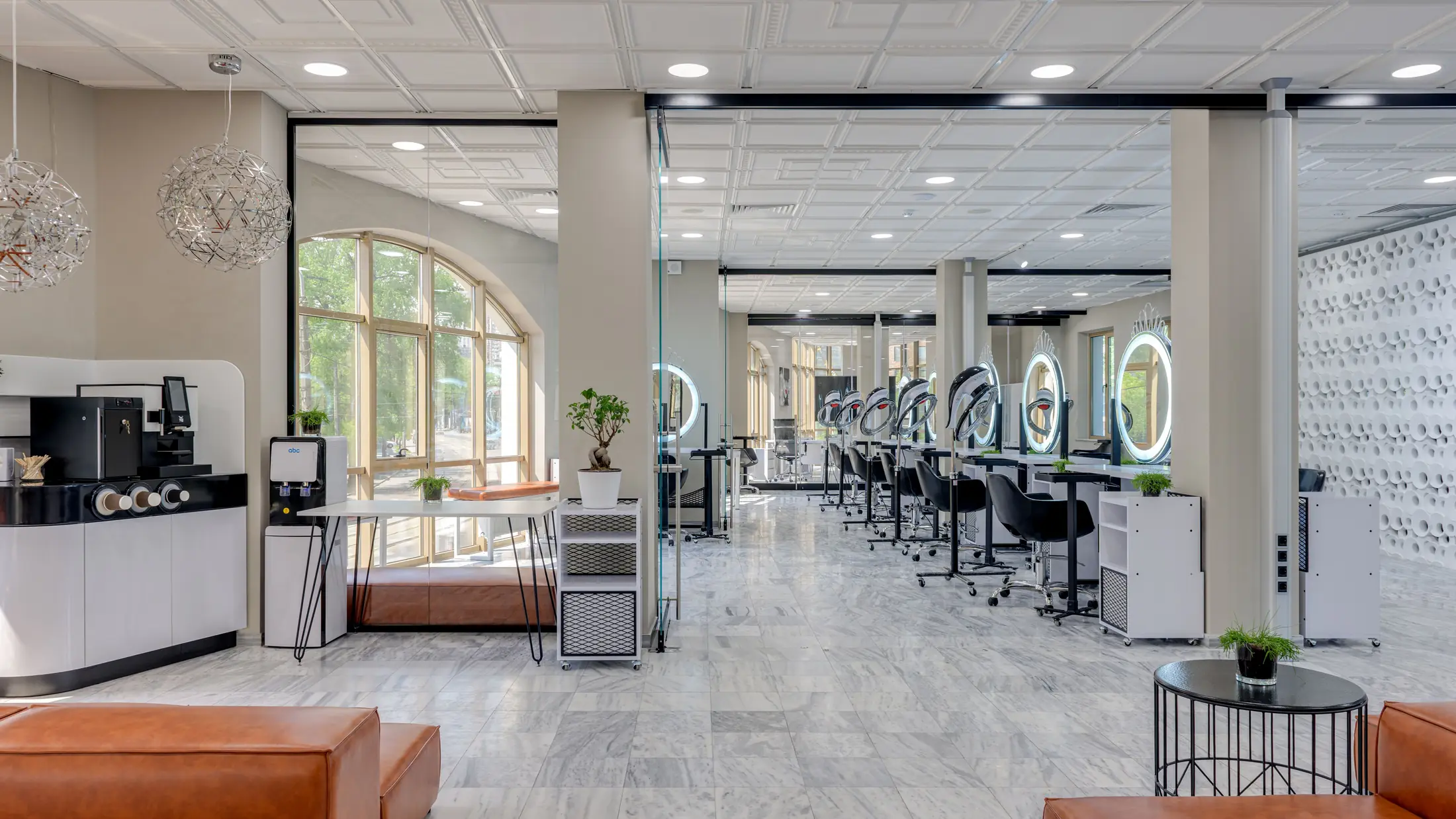 Comptoir d'accueil du salon, grande fenêtre cintrée et rangée de postes de coiffure